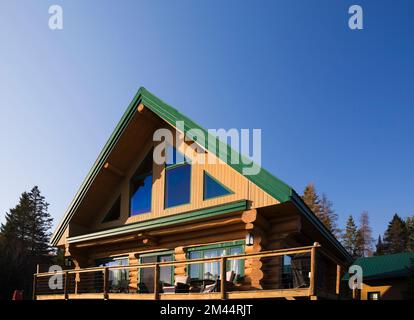 Rückansicht eines zweistöckigen Blockhauses im A-Rahmen-Stil mit grüner Verkleidung im Herbst. Stockfoto