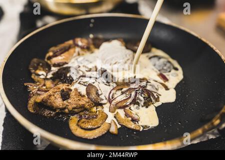 Pilzsauce-Konzept. Bolete-Pilze werden in der Pfanne gebraten. Geschmorte Sirloin-Teller-Zubereitung. Schwere Sahne in Saucen. Hochwertiges Foto Stockfoto