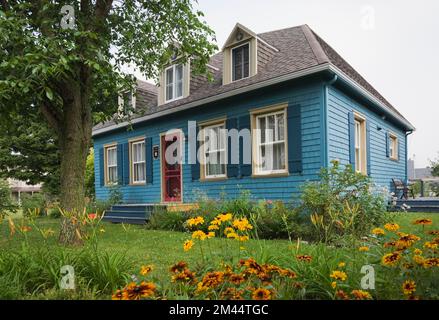 Alte blaue Hütte Stil Zedernschindeln verkleidet Haus mit rot bemalten Eingangstüren im Sommer. Stockfoto