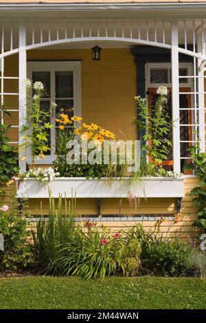 Alte Hausveranda mit weißem Holzgerüst und Blumenkasten im Sommer. Stockfoto