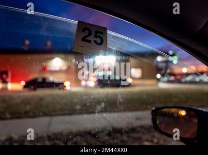 Fast Food Bestellnummernschild hängt am Fahrzeugfenster mit Autolinie und Abholung verschwommen im Hintergrund Stockfoto