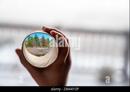 Kind, das einen Toilettenpapierschlauch aus Pappe als Teleskop hält, um sich eine andere Welt vorzustellen Stockfoto