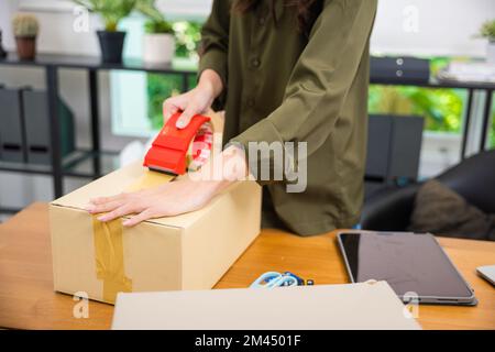 Nahaufnahmen, junge Frau, versiegelt mit Klebeband, große Pappschachtel Stockfoto