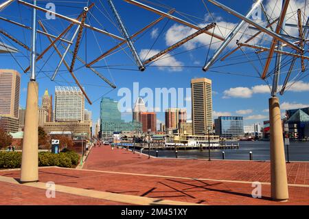 Die Skyline von Baltimore vom südlichen Ende des Inner Harbor aus gesehen, eingerahmt von einer Kunstausstellung mit Röhren im Science Museum Stockfoto