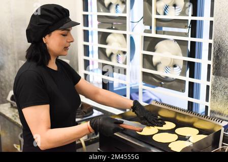 Eine Mexikanerin, die lacht, während sie Tacos in der Küche kocht Stockfoto