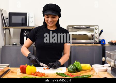 Eine Mexikanerin, die lacht, während sie Tacos in der Küche kocht Stockfoto