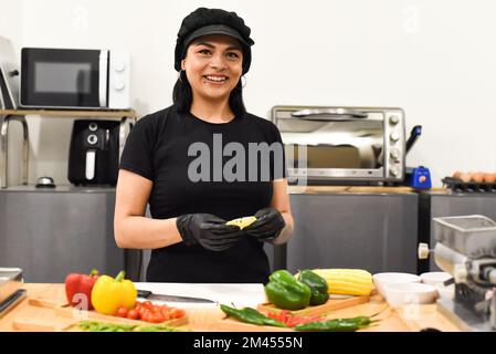 Eine Mexikanerin, die lacht, während sie Tacos in der Küche kocht Stockfoto