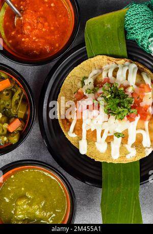 Taco condesa mit gebratenem Fisch auf schwarzem Teller mit mexikanischen Saucen Stockfoto