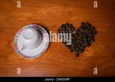 Eine Tasse Kaffee mit frisch gepflückten Kaffeebohnen, die ein Herz bilden Stockfoto