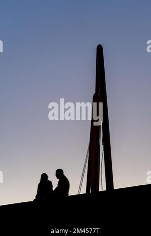 Dunkle Silhouette eines verliebten Paares beim Picknick vor dem Hintergrund eines orangefarbenen Sonnenuntergangs Stockfoto