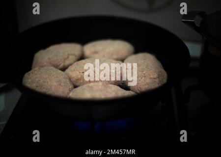 Große Schnitzel. Gebräuntes Fleisch. Halbfertigprodukt in der Küche. Ich koche Abendessen. Bratpfanne mit Essen. Stockfoto