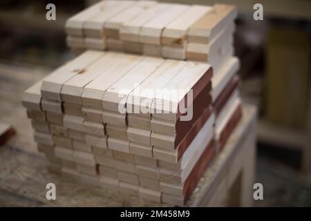 Rohlinge aus Holz. Vorstand in der Werkstatt. Details der Möbelproduktion. Tischlerei. Holzstangen. Stockfoto
