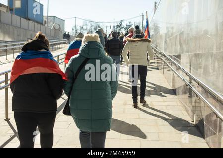 Im Frühling laufen die Menschen durch die Stadt. Bürger auf der Straße. Viele Menschen von hinten. Fußgänger gehen durch die Fußgängerzone. Stockfoto