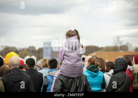 Viele Leute sehen sich die Show auf der Straße an. Menschen in der Stadt. Zuschauer der Leistung. Stadtfest. Viele Menschen von hinten. Stockfoto