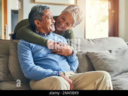 Dich zu lieben, wird nie langweilig. Ein liebevolles Seniorenpaar, das sich zu Hause auf dem Sofa entspannt. Stockfoto