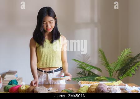 Nadelarbeit-Konzept, Frauen machen Blumen auf der Leinwand in Holzbügel mit Lochnadelstickerei. Stockfoto