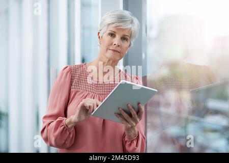 Sie nimmt ihr Geschäft sehr ernst. Porträt einer erwachsenen Geschäftsfrau, die ihr digitales Tablet bei der Arbeit verwendet. Stockfoto