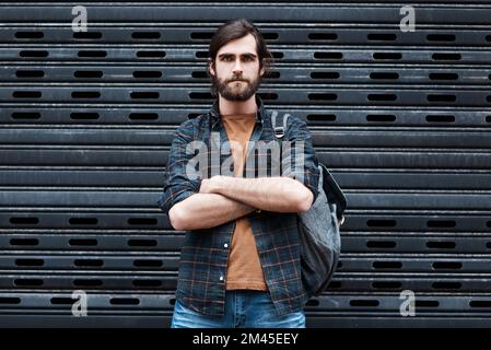 Er ist ein Mann auf einer Mission. Porträt eines gutaussehenden jungen Mannes, der mit gefalteten Armen vor grauem Hintergrund posiert. Stockfoto
