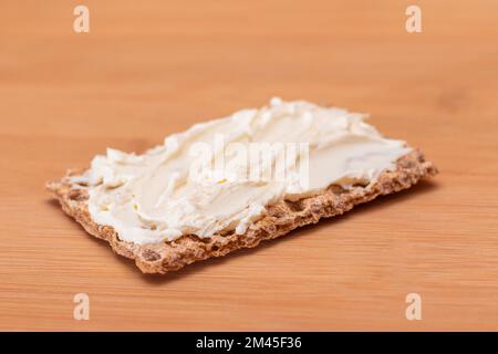 Vollkorn-Knäckebrot mit Frischkäse auf Bambus-Schneidebrett. Schnelle und gesunde Sandwiches. Gesunder Diätetischer Snack Stockfoto