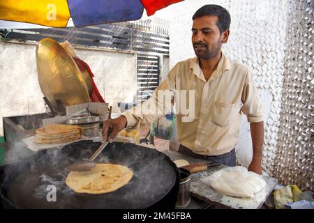 Männlicher Verkäufer, der Paratha an seinem Imbissstand am Straßenrand herstellt Stockfoto