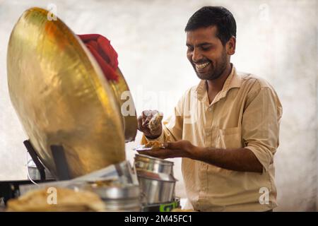 Männlicher Verkäufer, der Paratha mit Chhola kulcha an seinem Imbissstand am Straßenrand verkauft Stockfoto