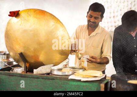 Männlicher Verkäufer, der Chhola kulcha für Kunden an seinem Imbiss packt Stockfoto