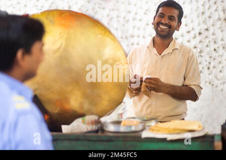 Männlicher Verkäufer, der Chhola kulcha für Kunden an seinem Imbiss packt Stockfoto