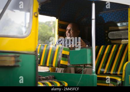 Auto-Fahrer mit Mobiltelefon, während er in der Auto-Rikscha sitzt Stockfoto