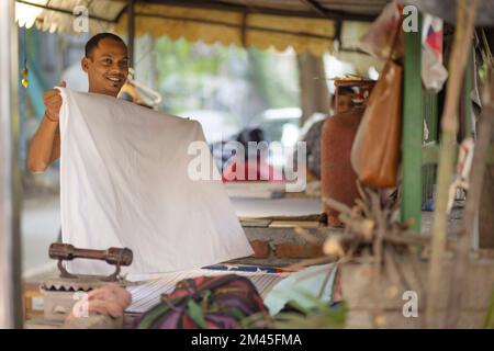 Indianer, Dhobi, Bügeln von Kleidung außerhalb einer Kolonie für ihre Bewohner Stockfoto