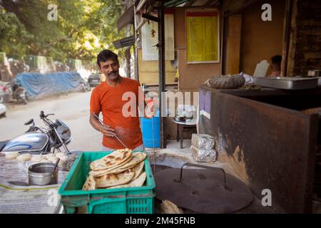 Koch eines lokalen Straßenrestaurants oder einer Dhaba, der Brot oder Roti in einem Tonholzofen oder einem Tandoor macht Stockfoto