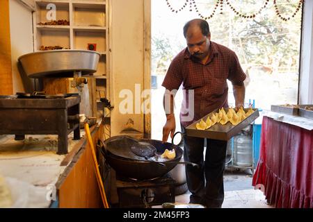 Besitzer eines Süßwarenladens, bekannt als Halwai Making Samosas, ein beliebter indischer Snack in der Küche seines Süßwarenladens Stockfoto