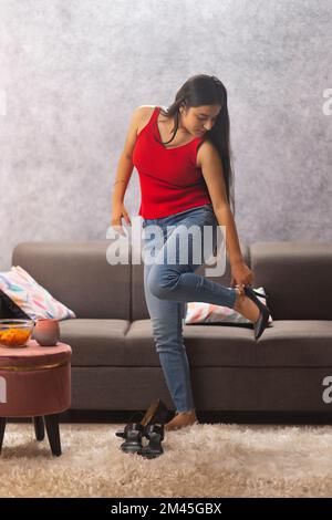 Teenager, der auf einem Bein steht und zu Hause High Heels anprobiert Stockfoto