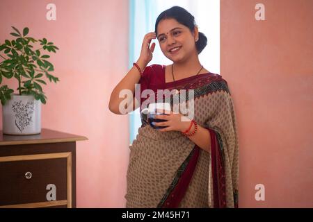 Porträt einer lächelnden Frau, die zu Hause mit einer Tasse Tee steht Stockfoto