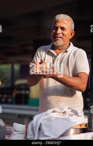 Männlicher Verkäufer, der an seinem Imbissstand am Straßenrand Kohle macht Stockfoto