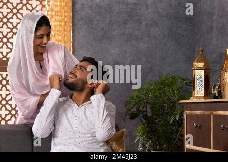 Portrait eines glücklichen, romantischen Paares, das sich im Wohnzimmer mit einem Lächeln ansieht Stockfoto