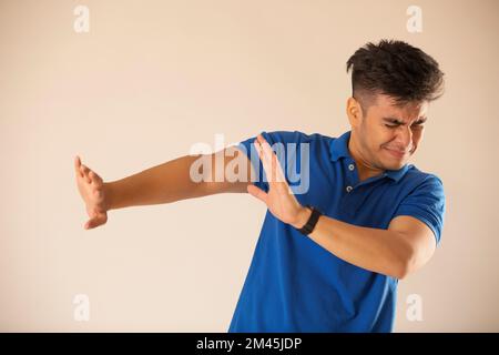 Frustrierter junger Mann, der eine Stoppbewegung vor weißem Hintergrund zeigt Stockfoto