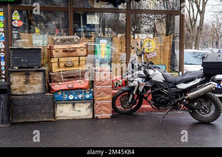 Bukarest, Rumänien, 4. Januar 2021: Dekorative alte Koffer und Motorrad vor einer Bar an sonnigen Wintertagen Stockfoto