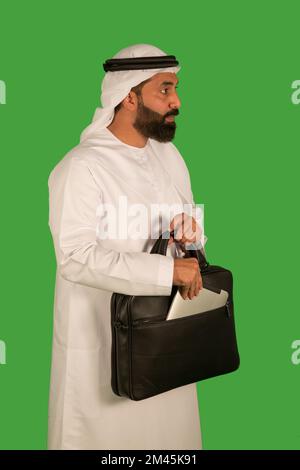Ein Mann aus den Emiraten, der ein digitales Tablet aus der Tasche zieht. Stockfoto