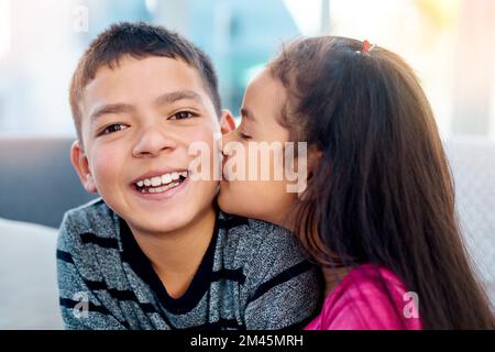 Okay, das hat sich nicht so schlecht angefühlt. Ein bezauberndes kleines Mädchen küsst zu Hause ihren großen Bruder auf die Wange. Stockfoto