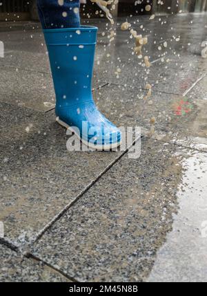 Ein lockerer Kopfsteinpflaster spritzt auf einen Kinderstiefel, wenn er darauf tritt. High-Speed-Aufnahmen Stockfoto