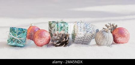Schneeweihnachtsdekorationen. Silberblaue, pinkfarbene, glänzende Bälle Geschenke liegen auf dem Schnee und funkeln. Das Konzept eines Urlaubs, Magie, Herzlichen Glückwunsch. Horizont Stockfoto