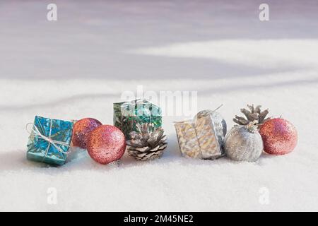 Schneeweihnachtsdekorationen. Silberblaue, pinkfarbene, glänzende Bälle Geschenke liegen auf dem Schnee und funkeln. Das Konzept eines Urlaubs, Magie, Herzlichen Glückwunsch. Horizont Stockfoto