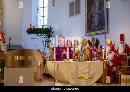 Altoetting, Deutschland-Dezember 17,2022 : Männer als St. verkleidet Nicholas hören während einer Messe auf der traditionellen jährlichen Pilgerfahrt zu. Stockfoto