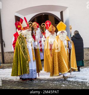 Altoetting, Deutschland-Dezember 17,2022 : Männer als St. verkleidet Nicholas verlassen die Kirche nach einer Messe während der traditionellen jährlichen Pilgerfahrt. Stockfoto