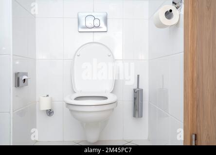 WC-Innenausstattung mit weißer Keramik-Toilettenschüssel. Modernes, minimalistisches Badezimmer im Hotel. Stockfoto