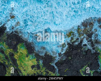 Fantastische schwarze Felsen an der Küste. Wellen brechen auf den Klippen. Mutter Erde natürliche Kraft ist auf dem Foto. Plantierte geologische Formationen Stockfoto