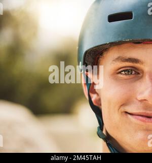 Nahaufnahme Porträt, Radhelm und Lächeln für einen Mann im Mountain Bike Park, Wettbewerb oder Wettbewerb. Fröhliche Radfahrerin, Gesichtszoom und Sicherheit beim Fahrradrennen Stockfoto