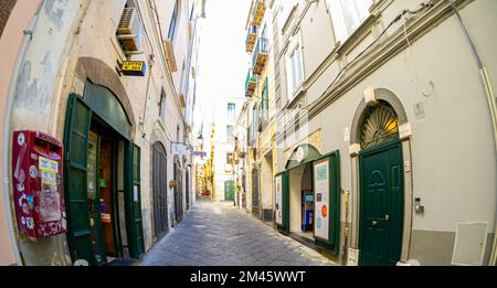 April 04 2022 - Neapel Italien - die überfüllte Straße eines Morgens mit vielen Motorroller und Leuten, die an alten bunten Gebäuden vorbeilaufen, um zu arbeiten Stockfoto