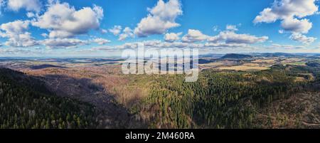 Wolken in blauem Himmel mit Schatten auf dem Boden. Ein Blick aus der Vogelperspektive auf wunderschöne Berge mit immergrünem Wald an sonnigen Herbsttagen. Natürliche Landschaft mit Bergketten und Tälern Stockfoto