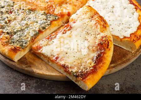 Pizza Quattro formaggi oder vier Käsesorten mit Tomatensoße, Parmesan, Mozzarella, Gorgonzola, Ricotta, als Nahaufnahme auf dem Holzbrett auf dem Tisch. Horizont Stockfoto